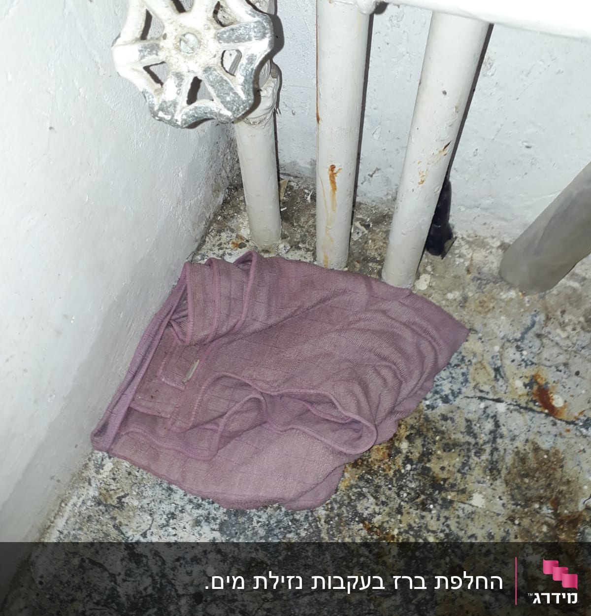 ברז ישן עם צינורות חלודים ומטלית סגולה
